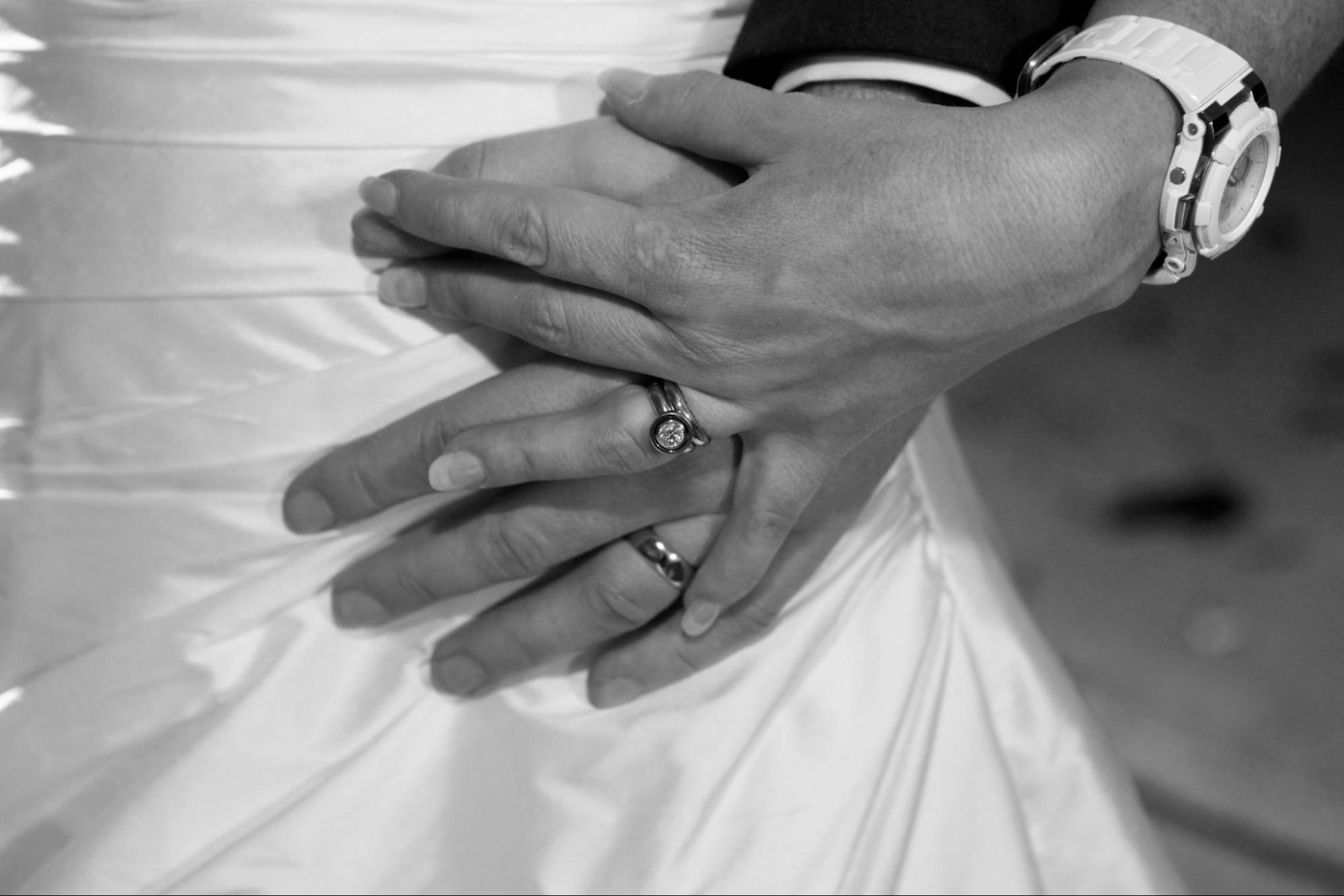 Bride and Groom wearing Rudolf Heltzel diamond and 18ct yellow gold engagement ring and wedding bands