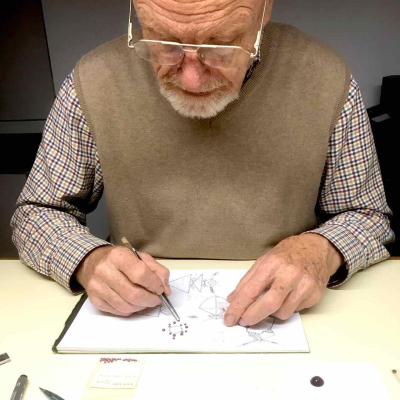 Rudolf Heltzel sitting at a desk sketching designs