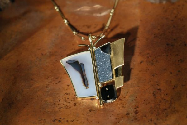 A custom 18ct yellow gold Rudolf Heltzel pendant on a brown marble surface